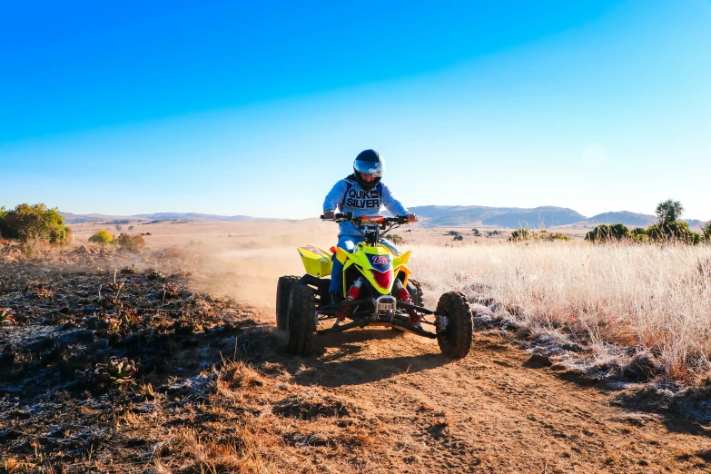 a man riding on the back of an atv while riding through grass and dirt