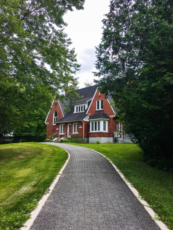 a red brick house with tall trees and grassy fields