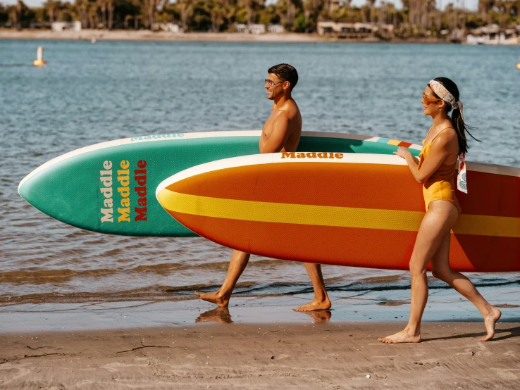 a man and woman are carrying surfboards on the beach