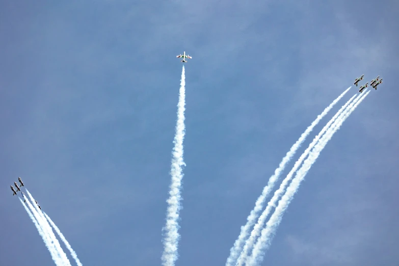 four airplanes flying sideways in the sky with smoke