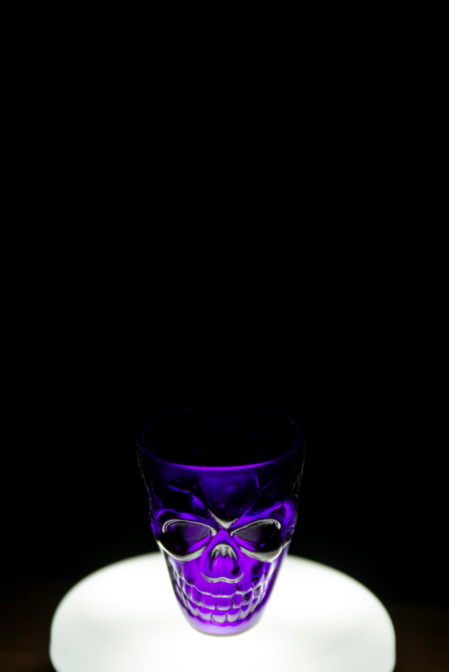 a purple glass skull on a table in the dark