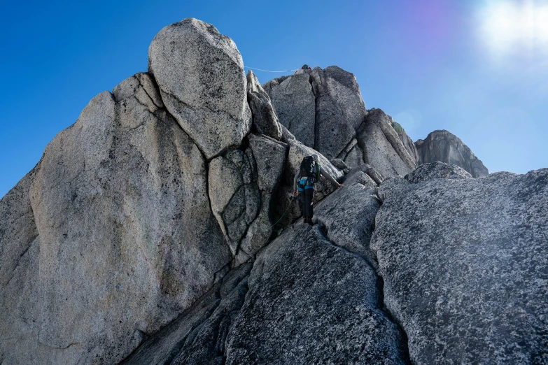 a man riding on top of a mountain under a blue sky