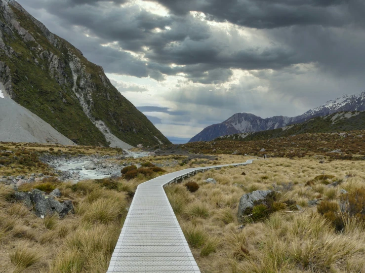 a path runs between hills that overlooks a mountain lake