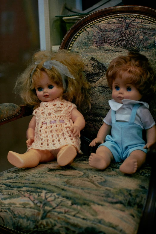 two dolls sitting on an old chair together