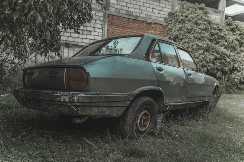 an old car sitting in grass near a building