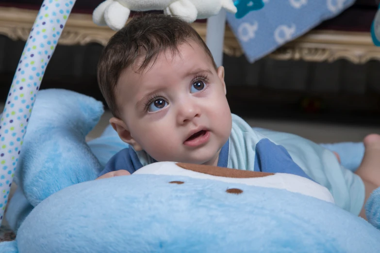 a very cute baby laying on a big blue stuffed animal