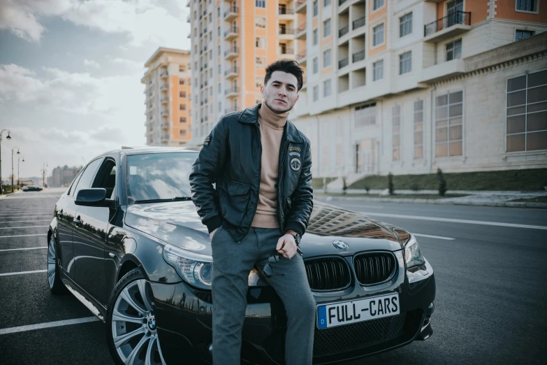 a man leaning against a black bmw car