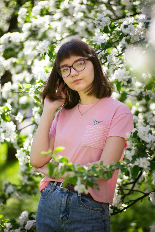 a  in glasses standing next to flowers