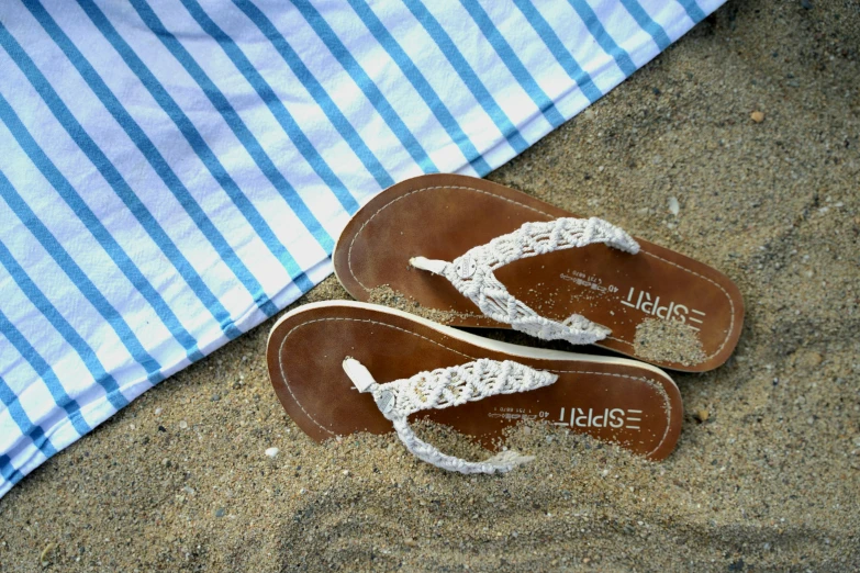 a pair of sandals in sand and a blue tarp