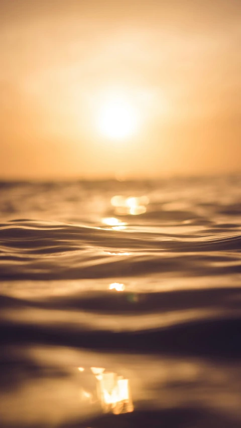 the sun shining on water with a small wave