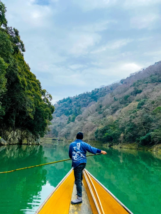 a man in a blue shirt rowing on a boat in a body of water