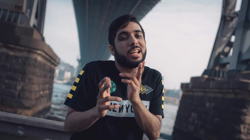 a man on a bridge with a black shirt and finger - prints