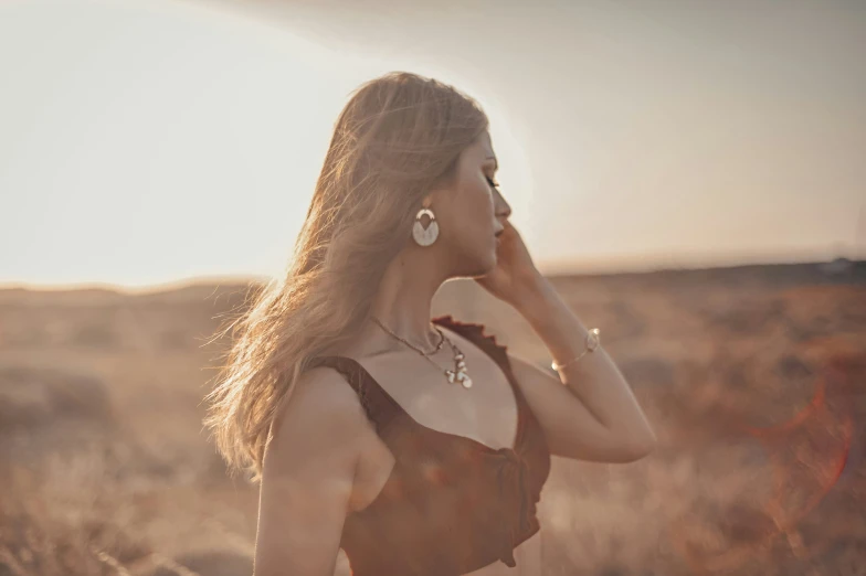 woman standing in open field at sunset with sun shining down