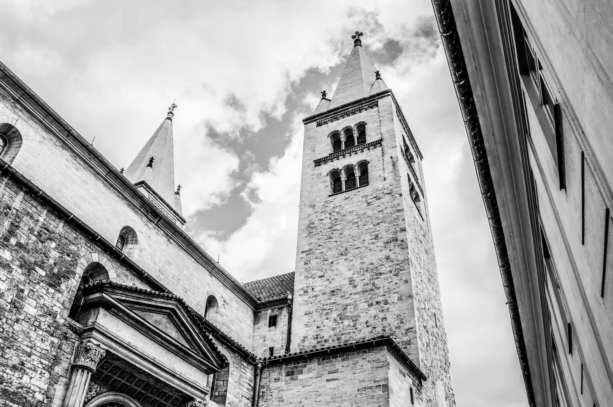 two brick buildings with steeples and windows under cloudy skies