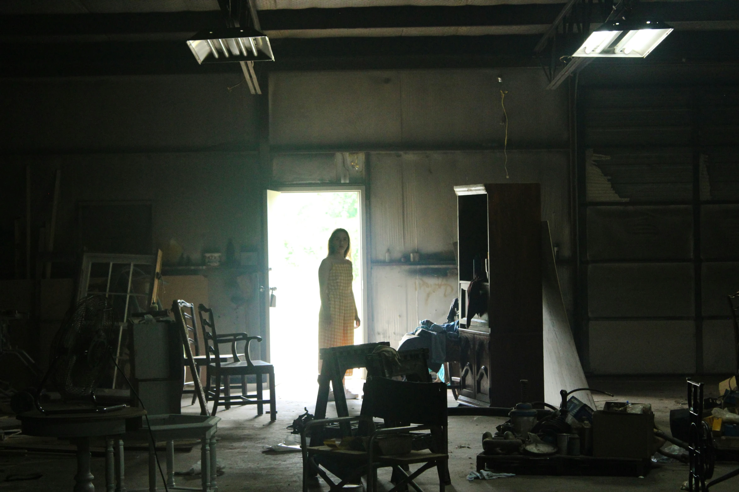 a woman stands in an open doorway with many pieces of furniture