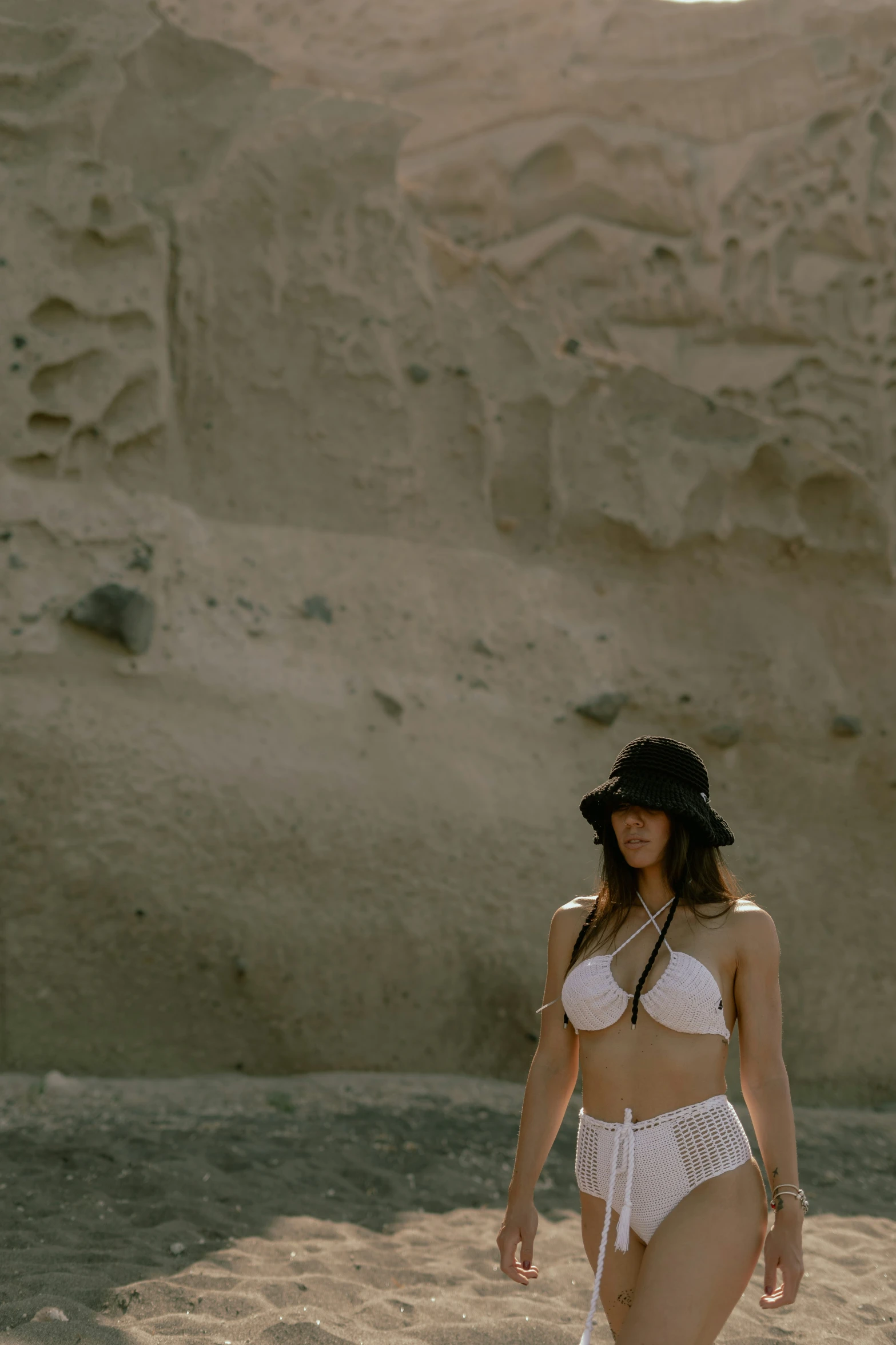 a woman in a bikini walking in the sand