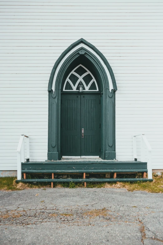 a green bench in front of a church with an arched door