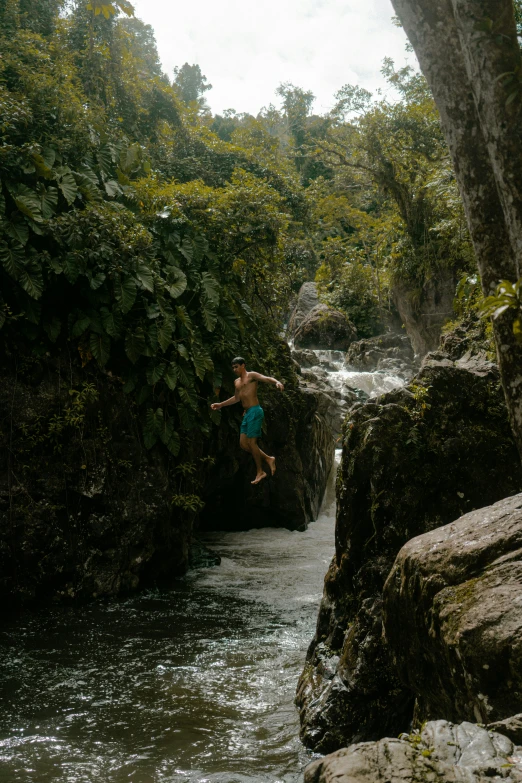 a person jumping in a creek and a rock wall