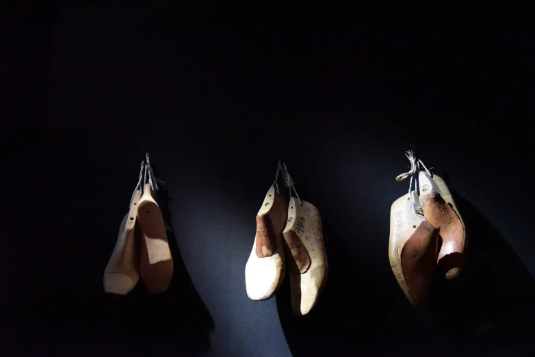 three pairs of ballet shoes hang on the wall