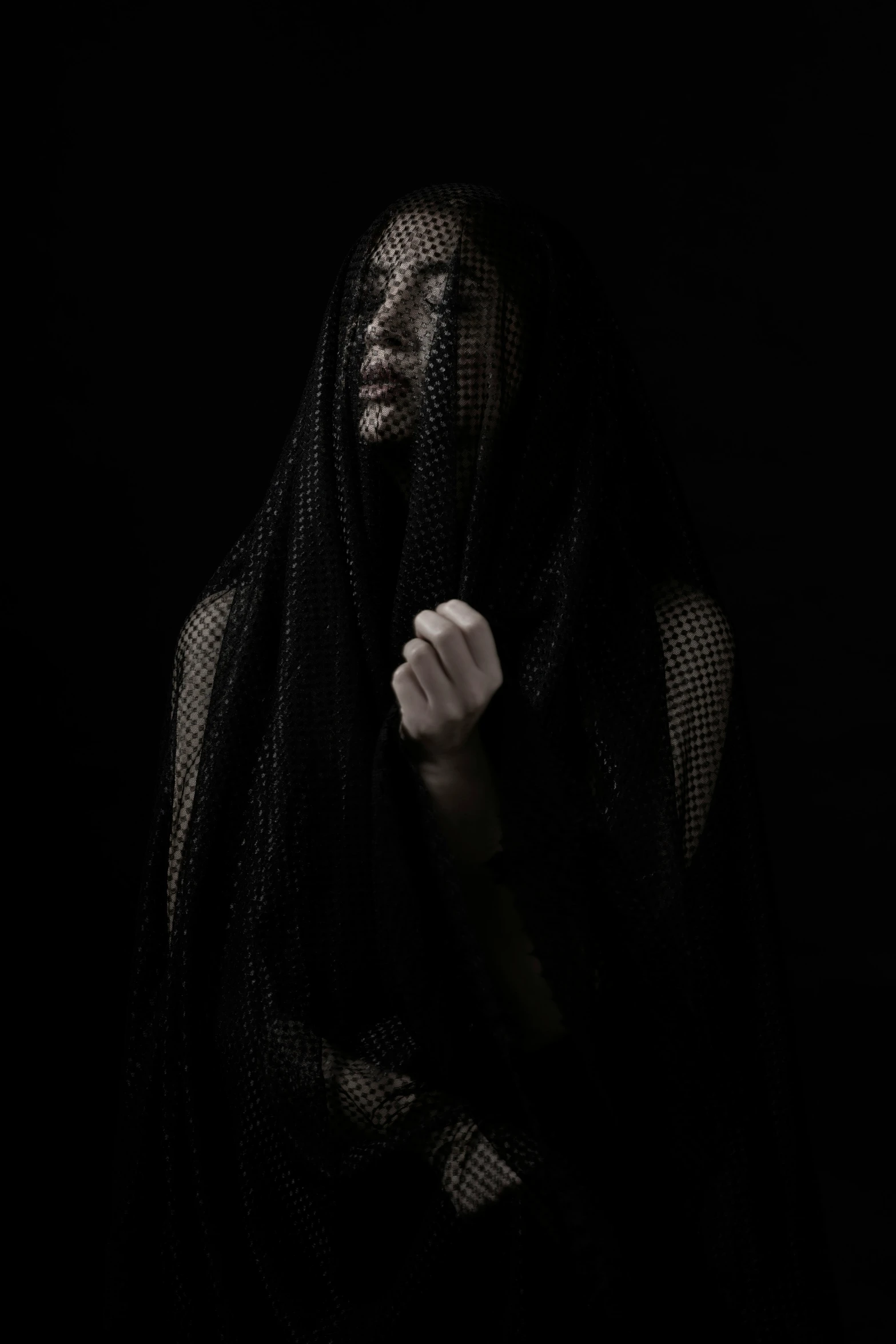 a woman wearing black veil with her hands folded out