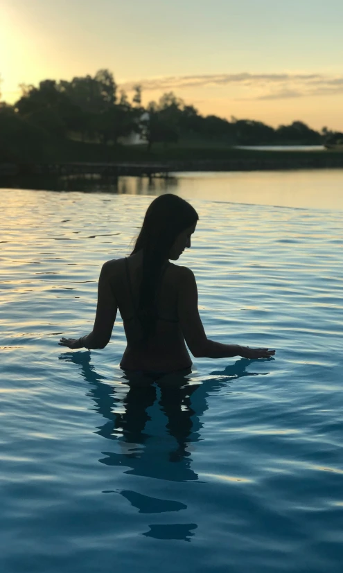 a woman sitting in the water holding her hands up