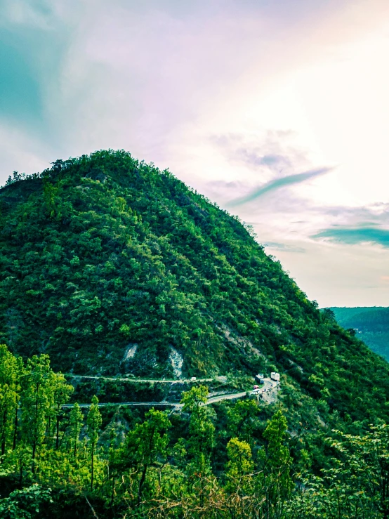 a lush green hillside under a cloudy blue sky