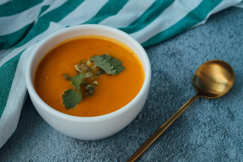 there is a white bowl filled with carrot soup