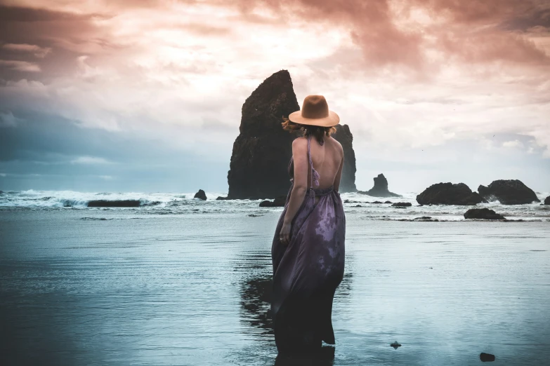 a person standing on the beach near rocks