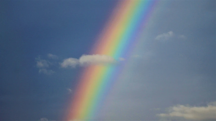 a rainbow in the sky with a blue cloud in background