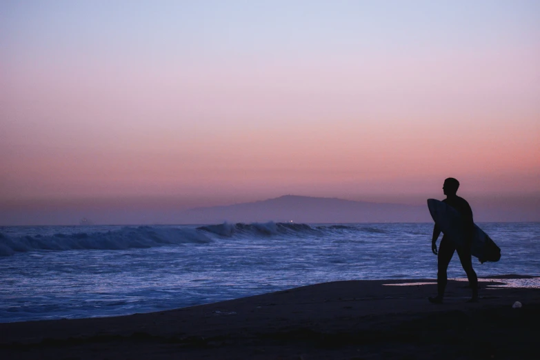 the lone man is standing on the beach with his surf board