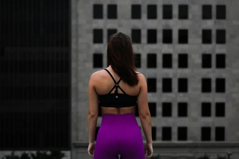 a young woman in bright purple is standing against the wall