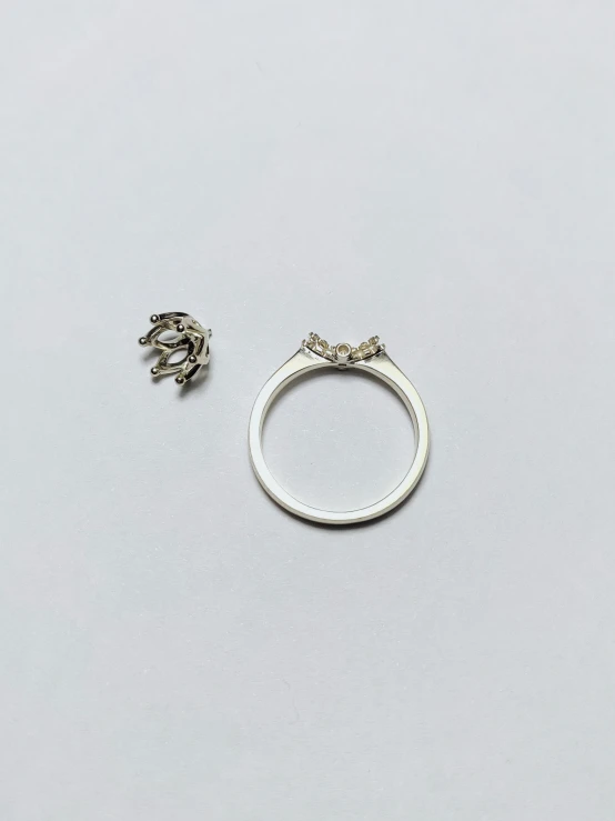 a white ring and two smaller pieces of silver on a gray surface