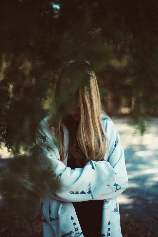 a  sits under trees while holding her arms crossed