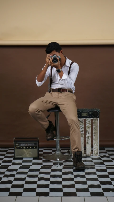 a man sitting on top of a stool with a camera