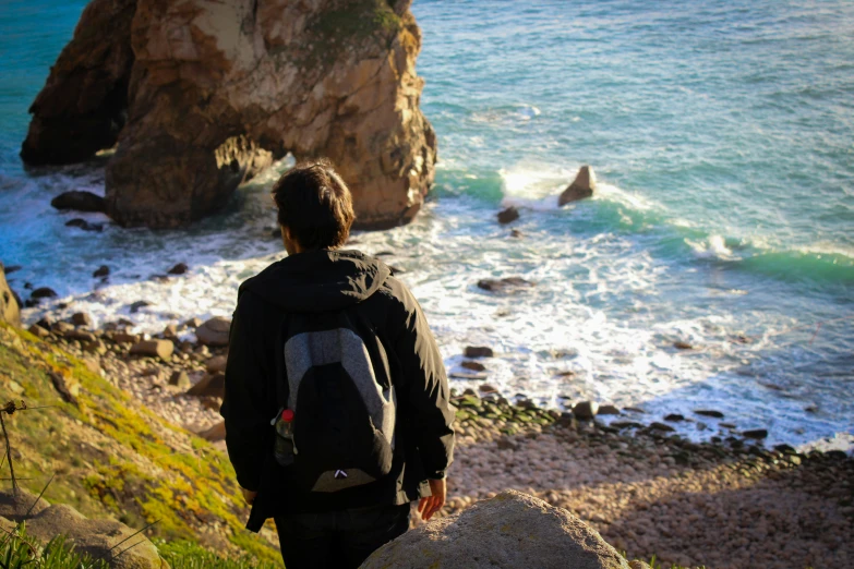 a man standing on a hill looking at the water