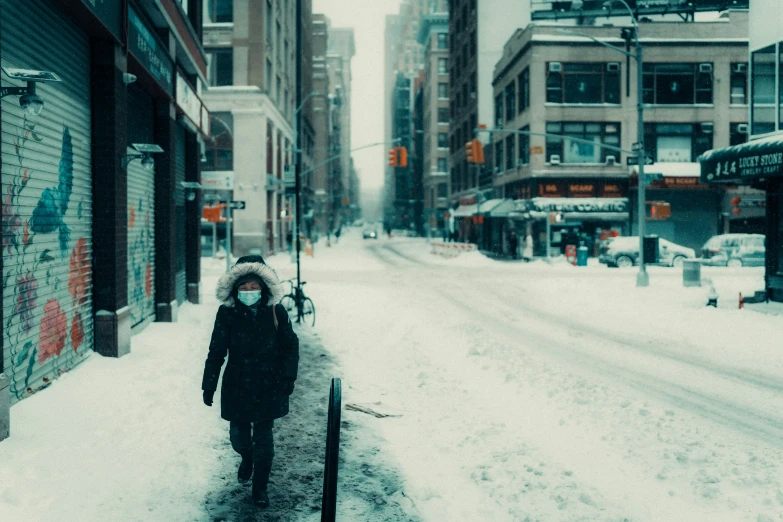 a woman walks down a city street in the snow