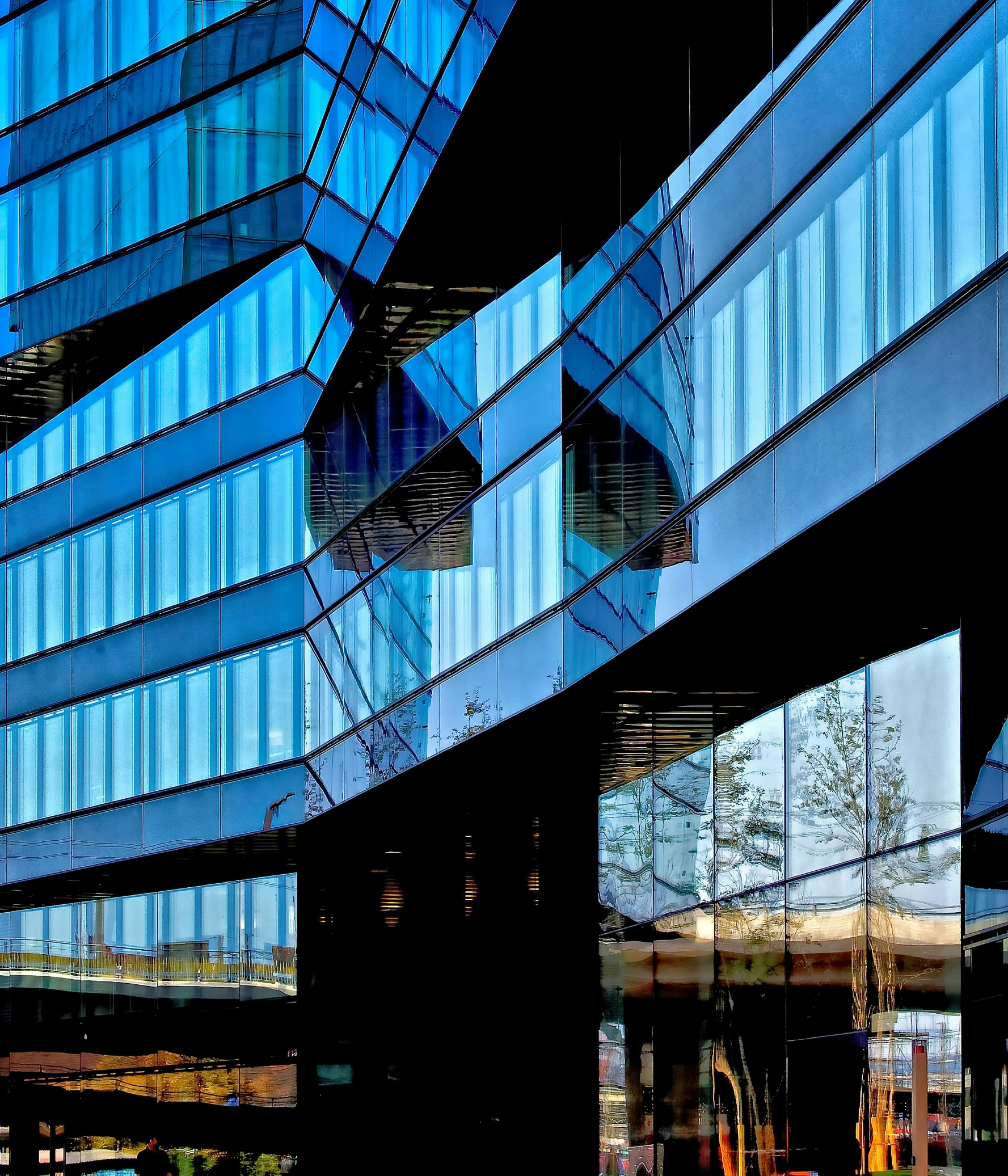 the building has glass walls and is reflecting the sky