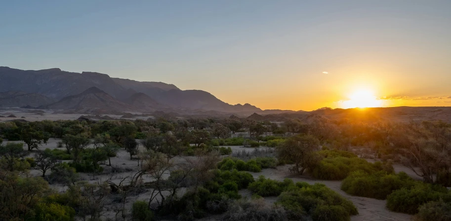 the sun sets in an overcast sky as it peeks through the desert