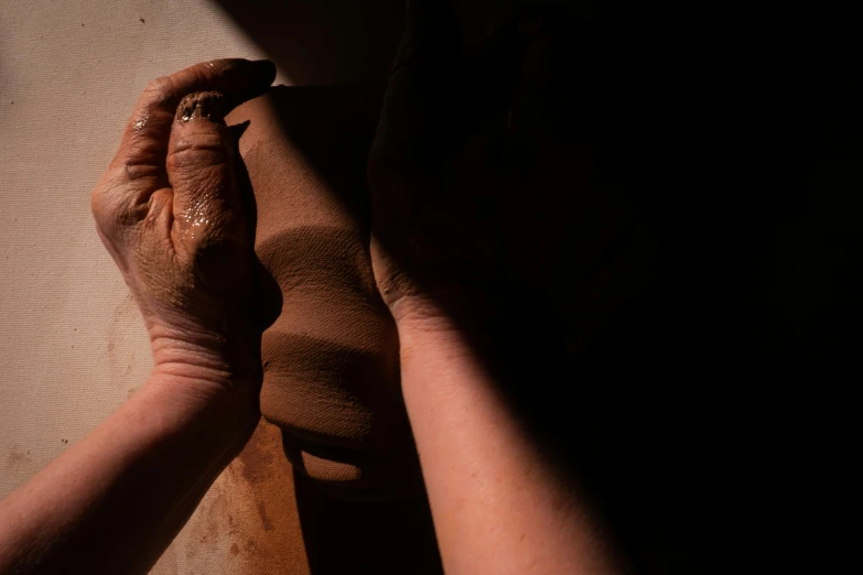 a woman is rubbing hands on a piece of pottery