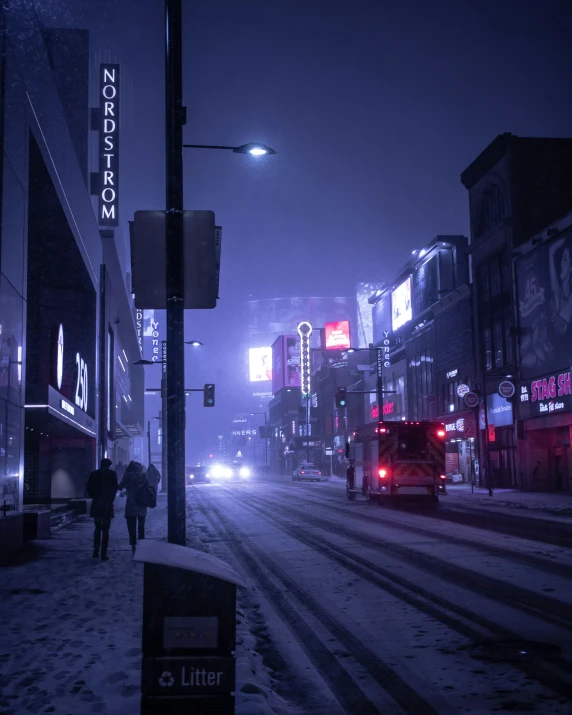 a city street in winter at night with snow on the ground and buildings