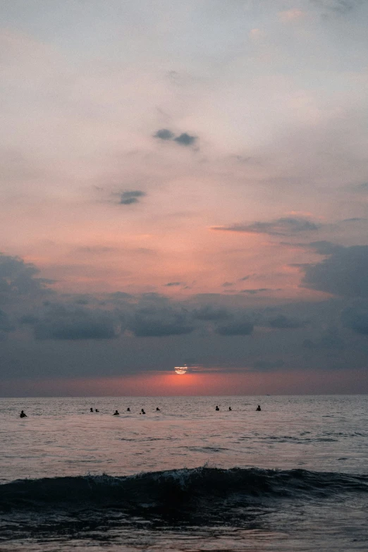 there is a lot of people that are in the water at sunset