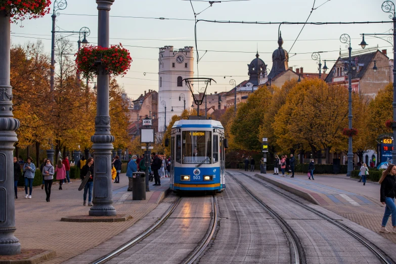 an electric streetcar is coming down the tracks to pick up passengers