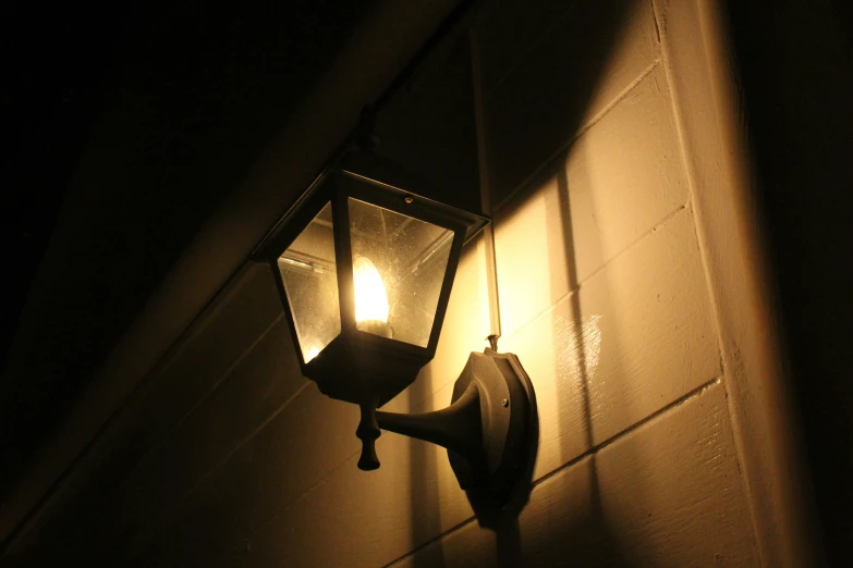 a lite up lantern in the dark near a brick wall