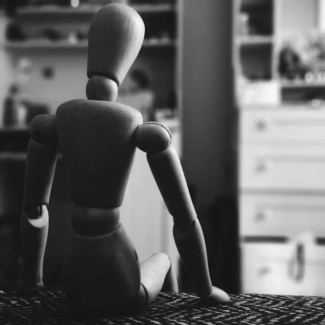 a wood toy sits on a wooden table in black and white