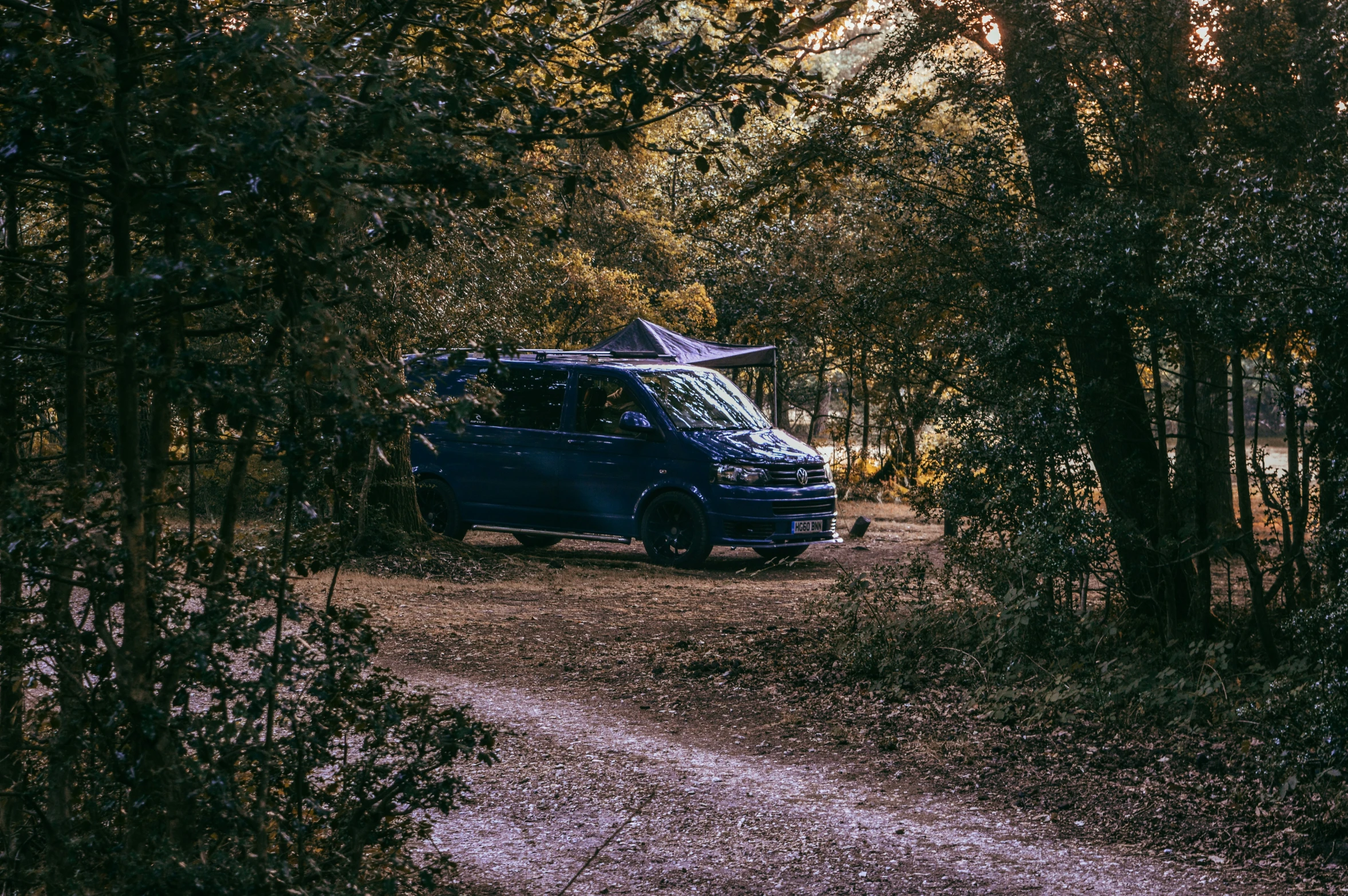 the van is parked near a trail in the woods