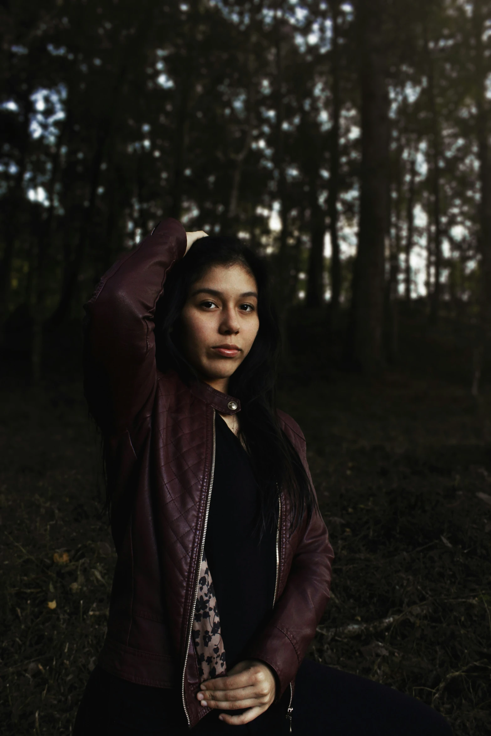 woman sitting in the woods with her hand on her head