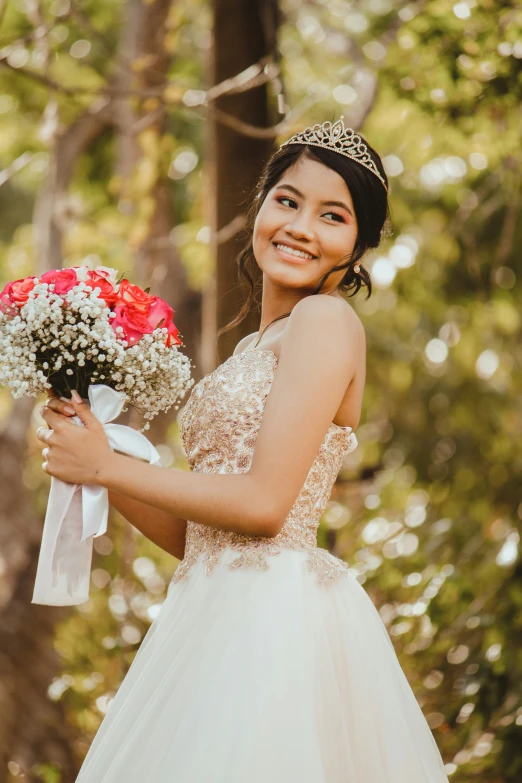 a woman holding a bouquet of flowers smiles as she looks off to the side