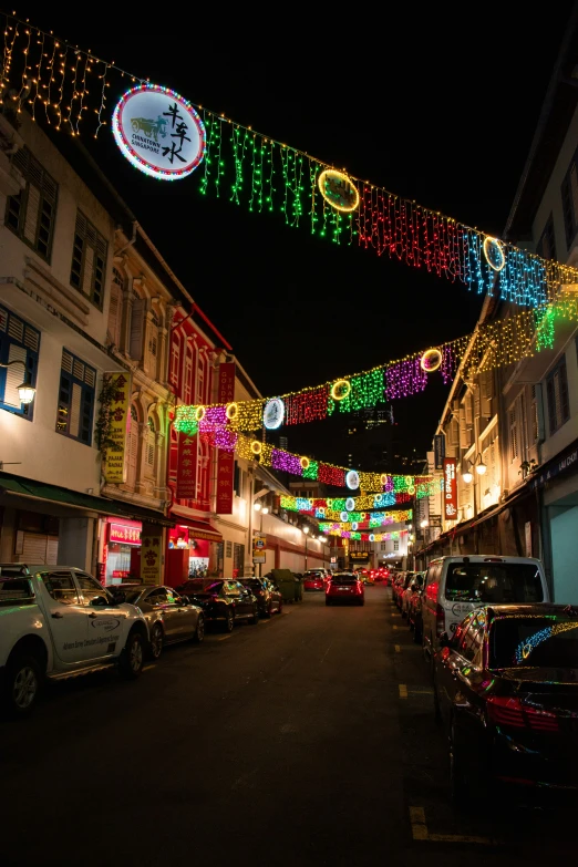 cars parked on the side of a street with christmas lights