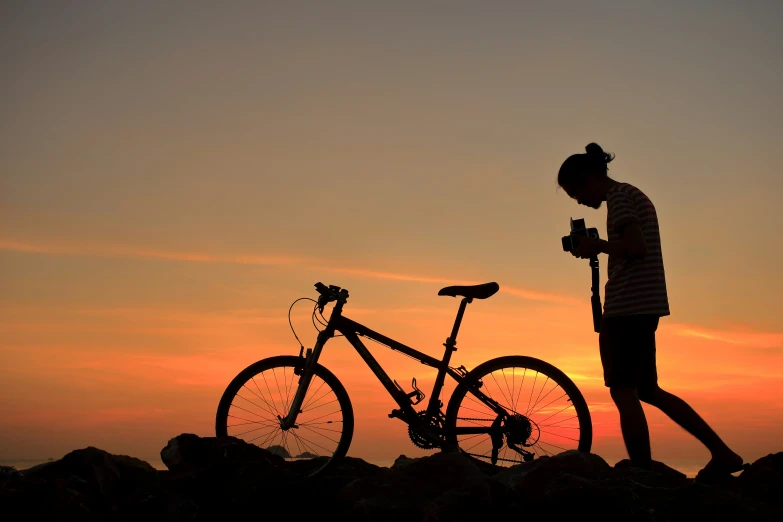 a person holding a bike on top of a rock