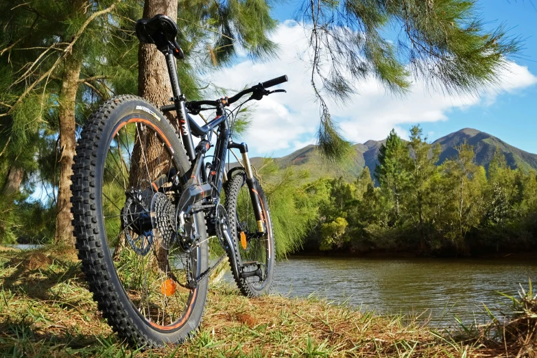 a bike is parked near the river, with mountains in the background